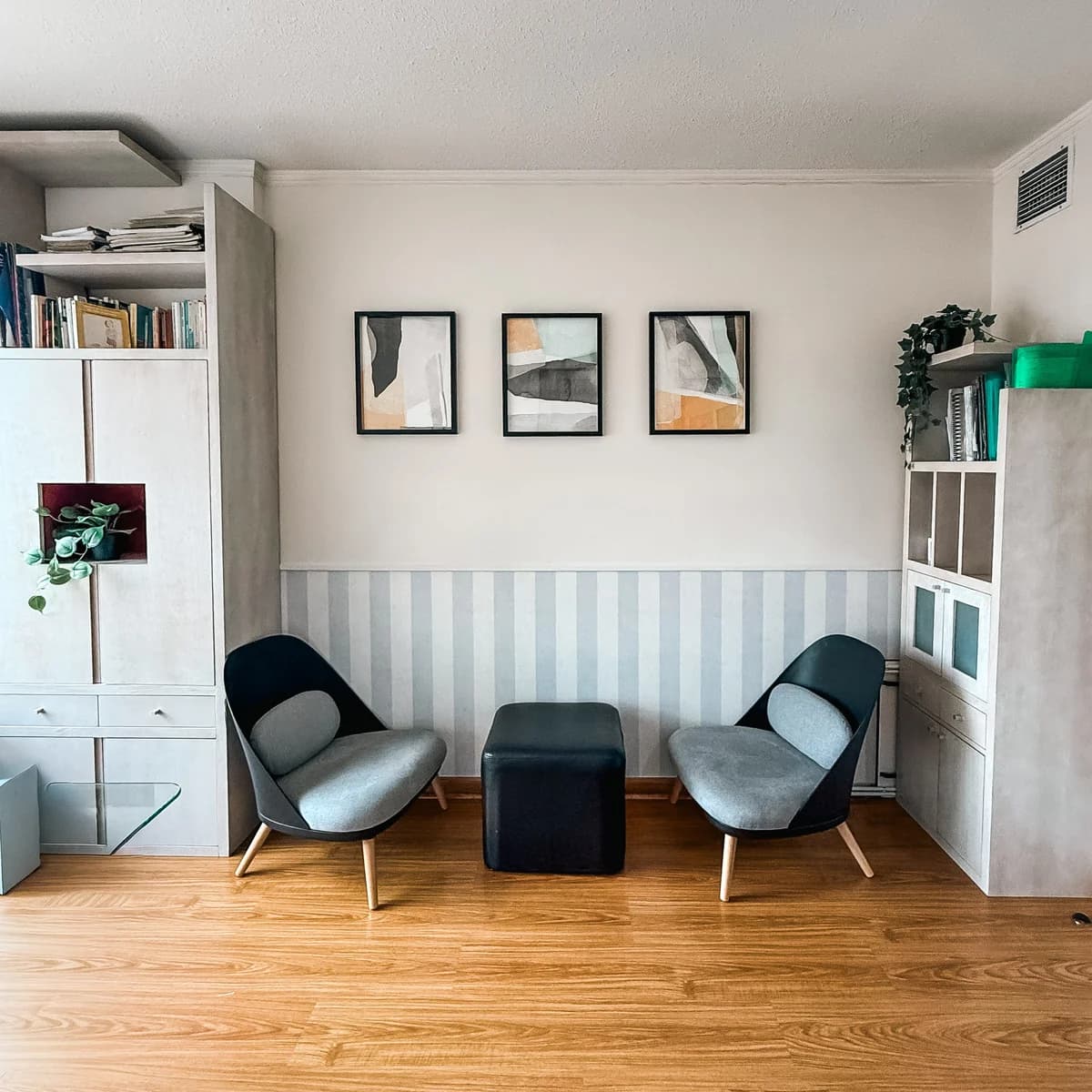 Sala de espera con sillones y tríptico de obras